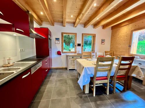 une cuisine avec des placards rouges et une table avec des chaises dans l'établissement Chalet tradition 6 pers avec cheminée, balcon et parking à Samoëns - FR-1-624-124, à Samoëns