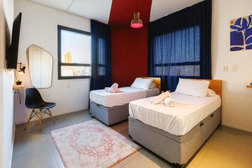 two beds in a room with a mirror and a chair at Hotel Centro 433 in São Paulo