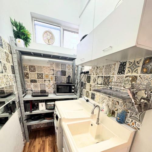 a small kitchen with a sink and tiles on the wall at Spacious Studio at citycentre in Singapore
