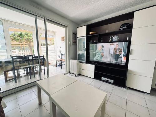 un salon avec une télévision et une table dans l'établissement Valras-Loc - Plaisir Balneaire, à Valras-Plage