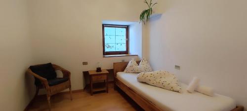 a room with a bed and a chair and a window at Große Wohnung mit Garagenparkplatz in Vols am Schlern