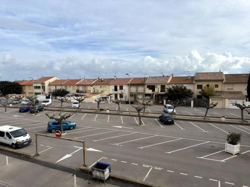 un parking avec des voitures garées devant un bâtiment dans l'établissement Valras-Loc - Evasion marine a deux pas de la plage, à Valras-Plage