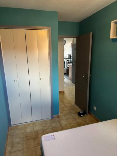 une chambre avec des murs verts et des armoires blanches et un couloir dans l'établissement Valras-Loc - Evasion marine a deux pas de la plage, à Valras-Plage