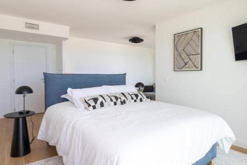 une chambre avec un grand lit blanc avec une tête de lit bleue dans l'établissement Valras-Loc Privatisez le 9e etage de lArchipel, à Valras-Plage
