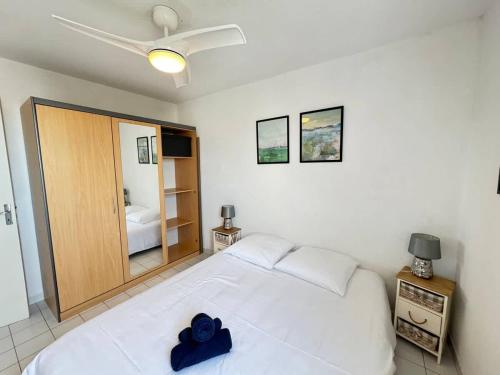 - une chambre dotée d'un lit blanc avec un objet bleu dans l'établissement Valras-Loc - Appartement du stade, à Valras-Plage