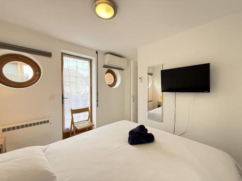 une chambre avec un lit blanc et une télévision à écran plat dans l'établissement Valras-Loc Villa Cecile - Maison Centre & Plage, à Valras-Plage