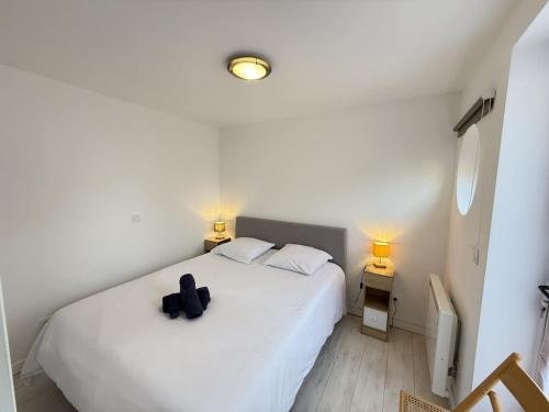 - une chambre dotée d'un lit blanc avec un objet noir dans l'établissement Valras-Loc Villa Cecile - Maison Centre & Plage, à Valras-Plage