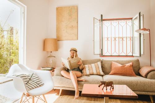 a woman sitting on a couch reading a book at Maria Tereza Sea Villa in Costa da Caparica