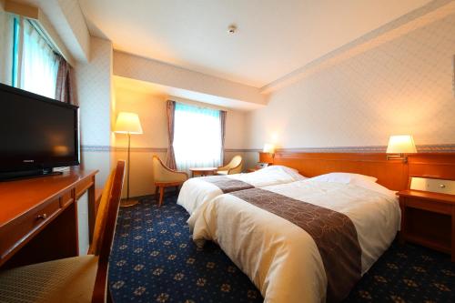 a hotel room with a bed and a flat screen tv at Hotel Seawave Beppu in Beppu