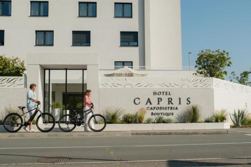 科佩尔Hotel Capris Capodistria Boutique的两个人在一栋建筑前推着自行车