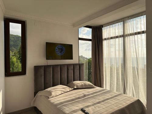 a bedroom with a bed and a large window at Horizon Hills Cottage- ჰორიზონ ჰილს in Kvariati
