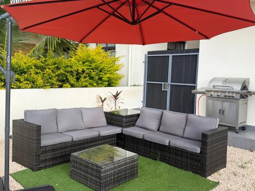 a patio with a couch and a red umbrella at Kensington Seaviews in Flic-en-Flac
