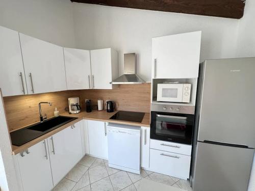 une cuisine avec des armoires blanches et un réfrigérateur blanc dans l'établissement Valras-Loc Maison des Orangers, à Valras-Plage
