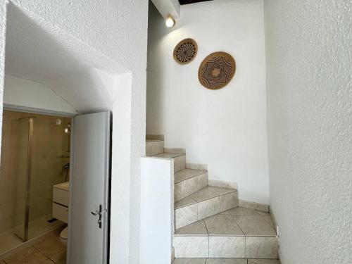 un couloir avec des escaliers et une horloge sur le mur dans l'établissement Valras-Loc Maison des Orangers, à Valras-Plage