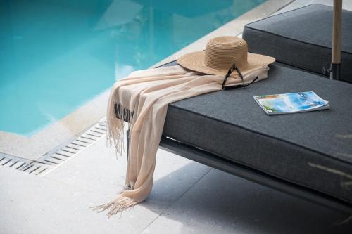 a hat and sunglasses sitting on a bed next to a pool at September15 Suites- Meganisi in Meganisi