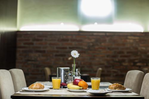 a table with plates of food and orange juice at Boutique Hotel Sopianae in Pécs