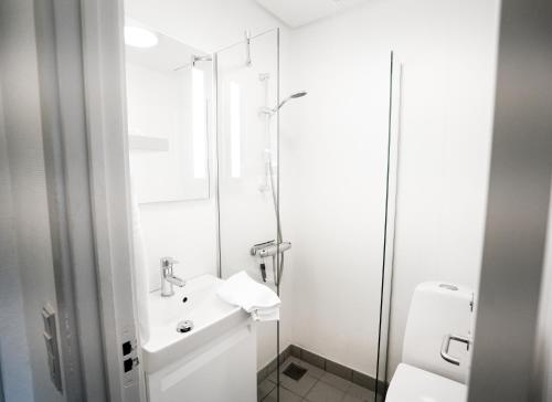a white bathroom with a sink and a shower at Hotel Juelsminde Strand in Juelsminde