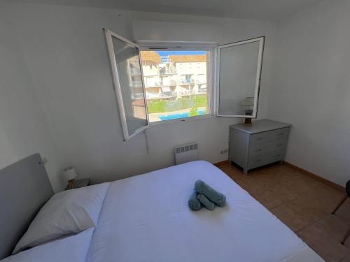 une chambre avec un lit blanc et une fenêtre dans l'établissement Valras-Loc Maison T3, à Valras-Plage