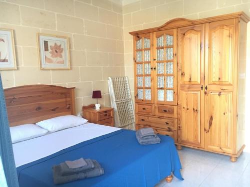 a bedroom with a bed and a wooden cabinet at Bright and Airy Flat in Marsalforn, Gozo in Marsalforn