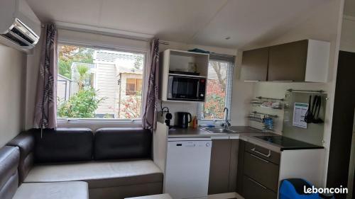 a small kitchen with a couch in a caravan at Mobilhome Clim Toboggans aquatiques in La Teste-de-Buch