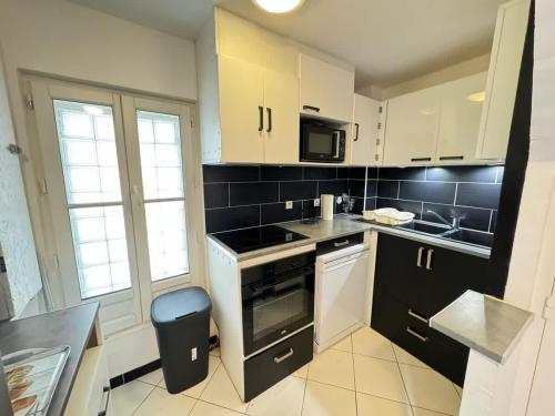 una cucina con mobili bianchi e un forno a piano cottura di Chambre Saint-Nazaire 3e Etage a Béziers