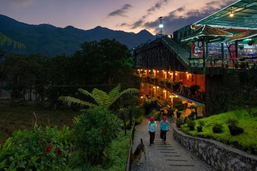 two people walking down a path in front of a building at MT House With Mountain View - Sa Pa Trekking Tour in Sa Pa