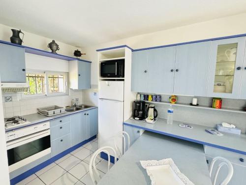 une cuisine avec des placards bleus et blancs et une table dans l'établissement Valras-Loc Maison de ville avec terrasse, à Valras-Plage