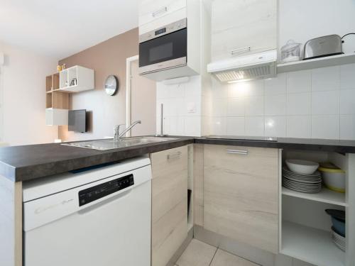 une cuisine blanche avec un évier et un comptoir dans l'établissement Valras-Loc La Dune - Evasion Familiale, à Sérignan