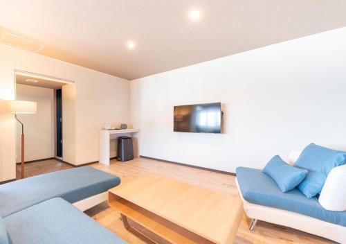 a living room with a blue couch and a table at LiVEMAX RESORT Atami OCEAN in Atami