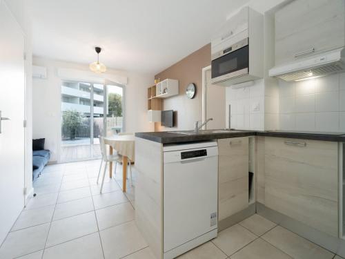 une cuisine avec des appareils électroménagers blancs et une salle à manger dans l'établissement Valras-Loc La Dune - Evasion Familiale, à Sérignan