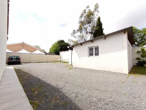 ein weißes Gebäude mit einem daneben geparkten Auto in der Unterkunft Nid du Merle, Pessac in Pessac