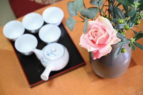 a vase with a rose in it next to a table at Asakusa Ginza direct access to the airport in Tokyo