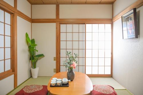 ein Zimmer mit einem Tisch mit Tassen und Blumen darauf in der Unterkunft Asakusa Ginza direct access to the airport in Tokio