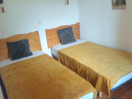 Dos camas en una habitación pequeña con sábanas amarillas. en Charmant 2 Pièces pour 4 Personnes avec Balcon et Accès Piscine à Superdevoluy - FR-1-504-549, en Le Dévoluy