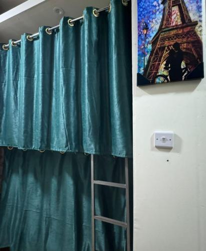 a bathroom with a green shower curtain and a ladder at Tariq Alqima Holiday Homes Rental in Dubai