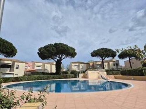 une grande piscine avec des arbres et des bâtiments dans l'établissement Appartement familial 3 pièces, piscine, terrasse et parking privé - Cap d'Agde - FR-1-249-368, au Cap d'Agde