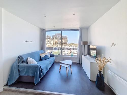 un salon avec un canapé bleu et une fenêtre dans l'établissement Appartement à Courseulles-sur-Mer avec Vue sur Port et Parking - FR-1-746-33, à Courseulles-sur-Mer