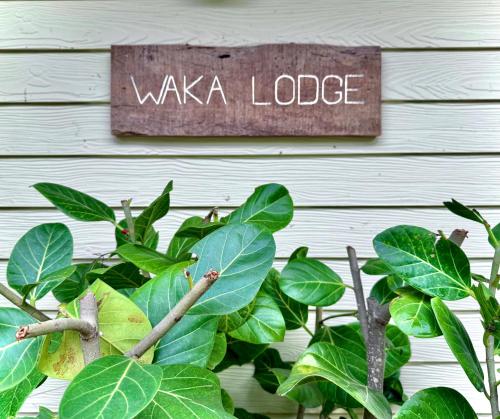 a sign that reads wakeka lodge next to a plant at Waka Lodge - House with garden in Blue Bay