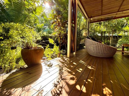 a porch with two plants and a hammock on it at Waka Lodge - House with garden in Blue Bay