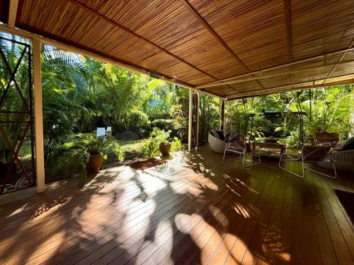 a porch with a wooden deck with chairs and trees at Waka Lodge - House with garden in Blue Bay