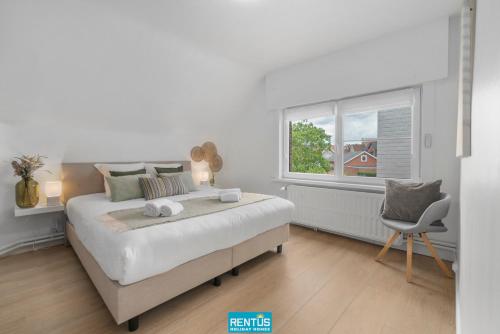 a white bedroom with a large bed and a chair at Coppietershof - spacious home with garden near historic Bruges in Bruges