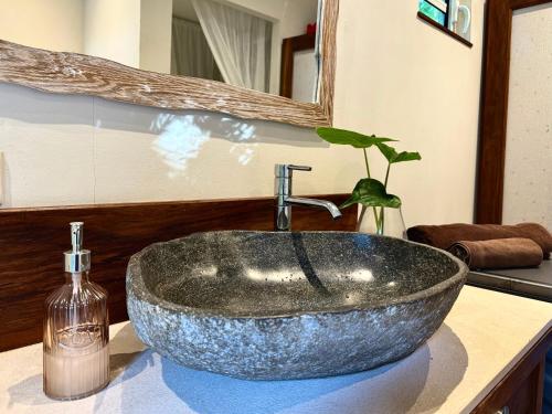 a bathroom sink with a large stone sink at Waka Lodge - House with garden in Blue Bay