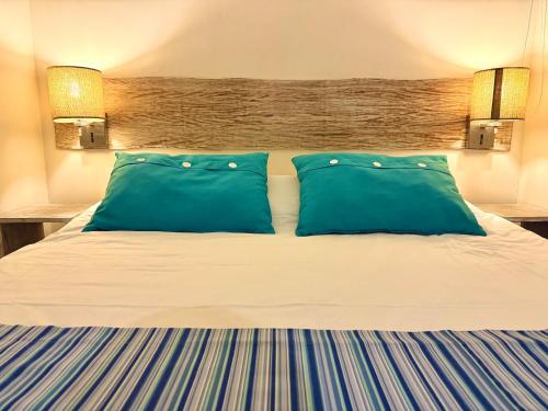 a bed with two blue pillows in a hotel room at Waka Lodge - House with garden in Blue Bay