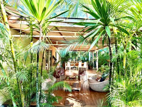a greenhouse with palm trees and a table and chairs at Waka Lodge - House with garden in Blue Bay