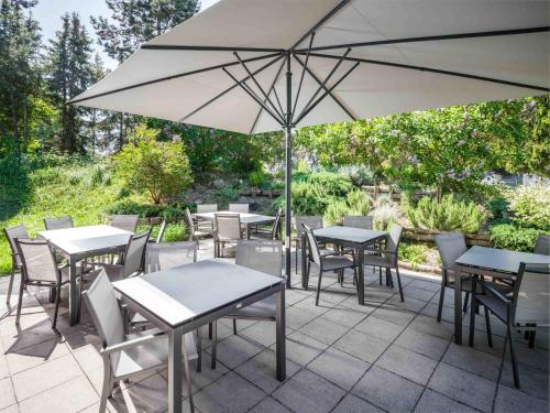 a patio with tables and chairs and an umbrella at Hotel Speyer am Technik Museum in Speyer