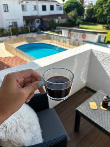 a person holding a cup of coffee next to a pool at The Summer Haven in Polis Chrysochous