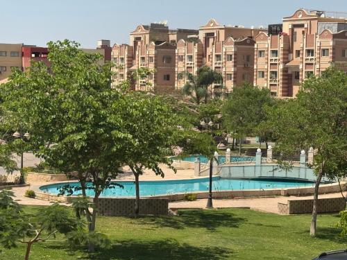 a large apartment building with a swimming pool and trees at Zayed continental Apartment in Sheikh Zayed