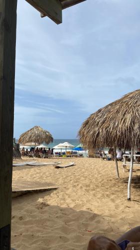 a beach with some straw umbrellas and the ocean at Luxury Villa Pool and BBQ in San Juan Lakes Los Colales RD in Punta Cana