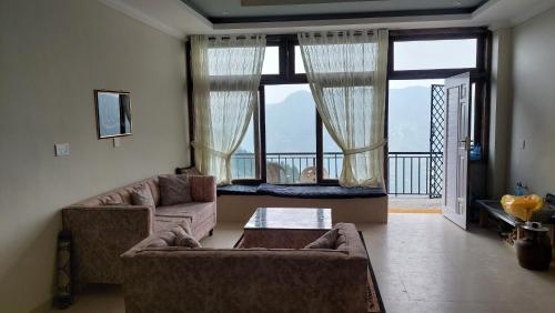 a living room with a couch and a large window at HK Heights - Sunset Valley Retreat in Nathia Gali