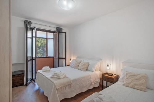 a white bedroom with two beds and a window at Tra Monti E Mare in Cisano sul Neva